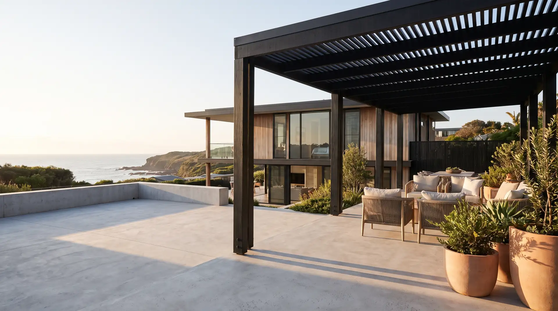 Honed concrete alfresco patio beside a coastal home